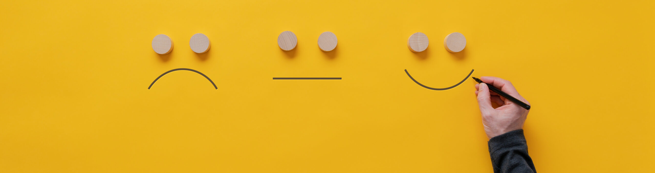 Customer feedback and satisfaction conceptual image - male hand drawing happy, sad and neutral faces over yellow background.